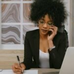 Businesswoman making a phone call while working at the desk, focused and professional.