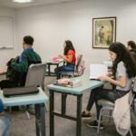 Students engaged in study inside a college classroom with books and discussions.
